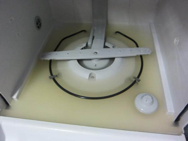 A mosogatógép allján sárgás, koszos víz áll.
